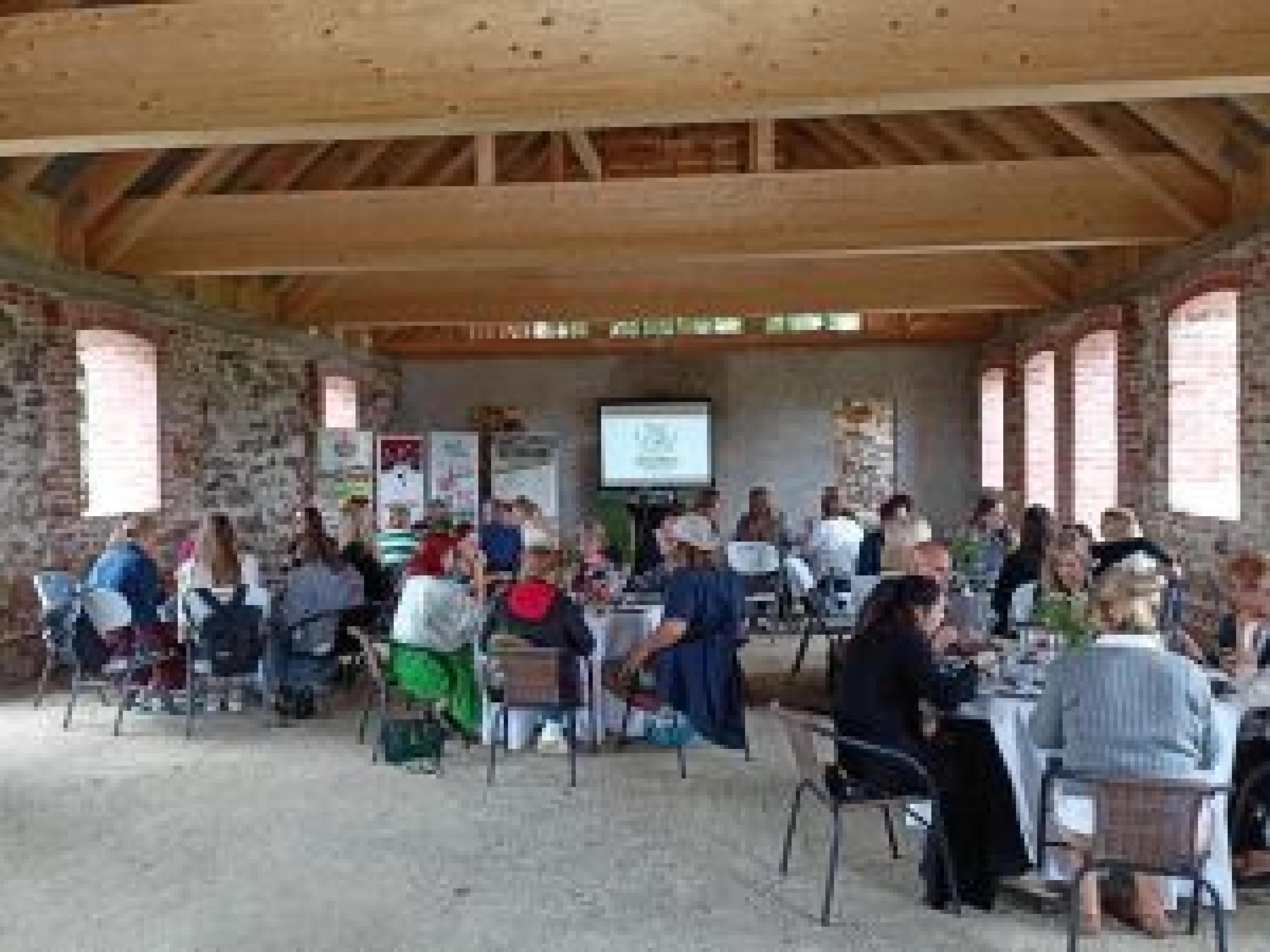sala konferencyjna osoby siedzące tyłem patrzące na prezentacje na ekranie na drugim tle